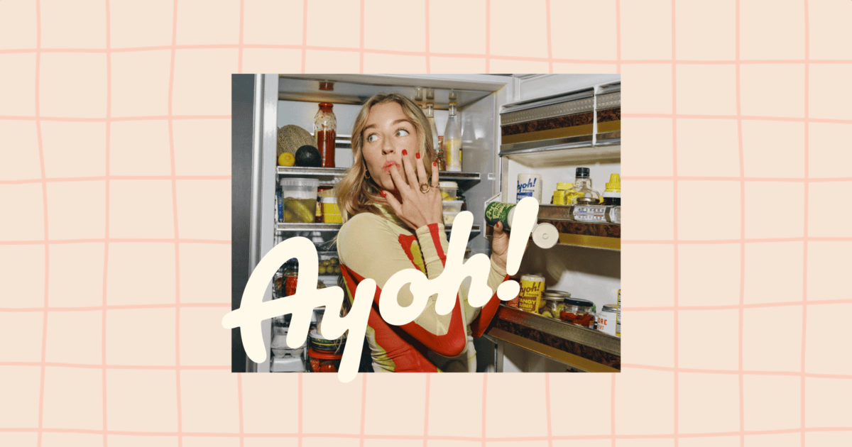 Woman standing in front of an open refrigerator, touching her mouth with a surprised expression; the word "Ayoh!" is overlaid in large text. | Wonderly