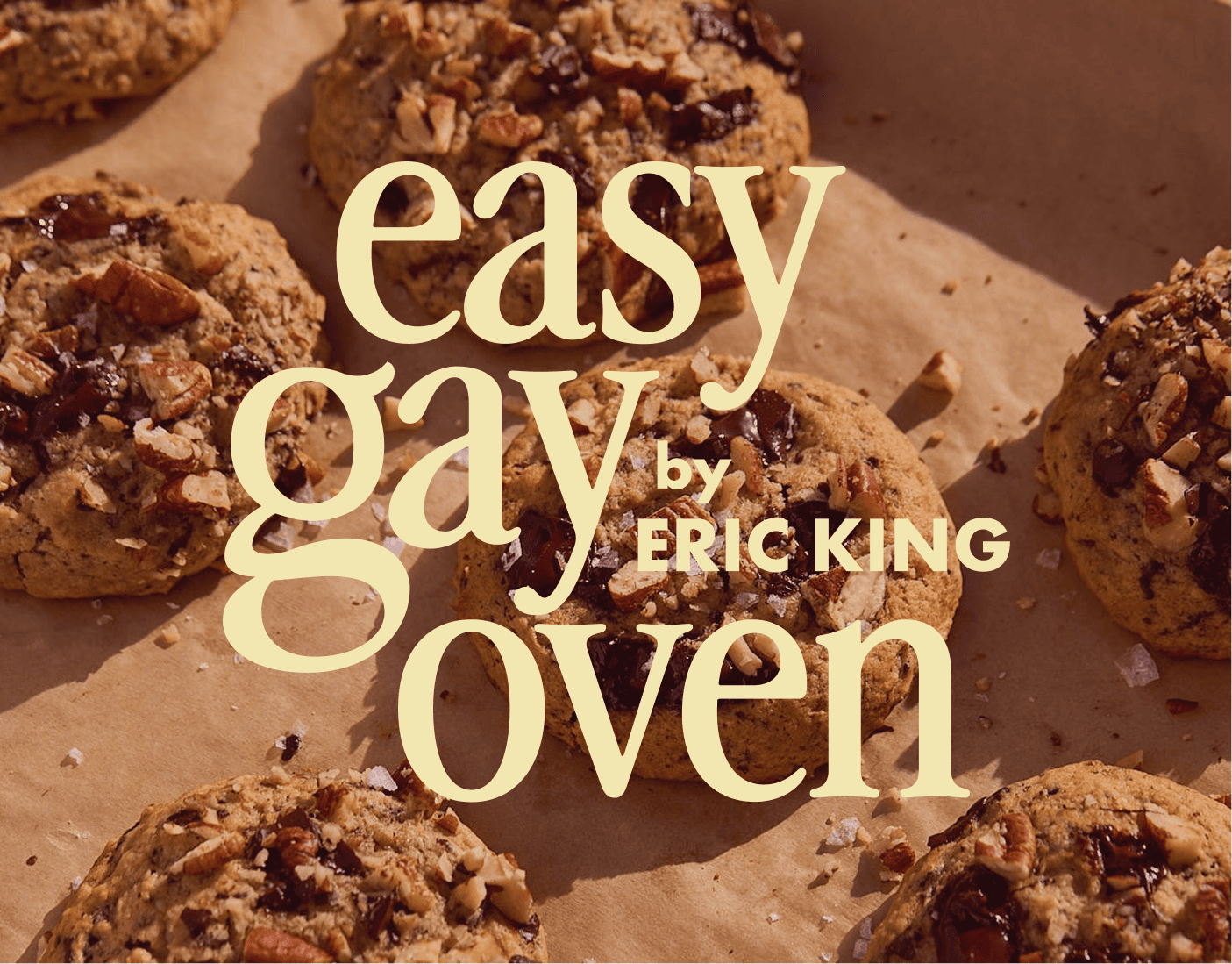 Chocolate chip cookies with nuts on parchment paper. Large text overlaid reads, "easy gay oven by Eric King. | Wonderly
