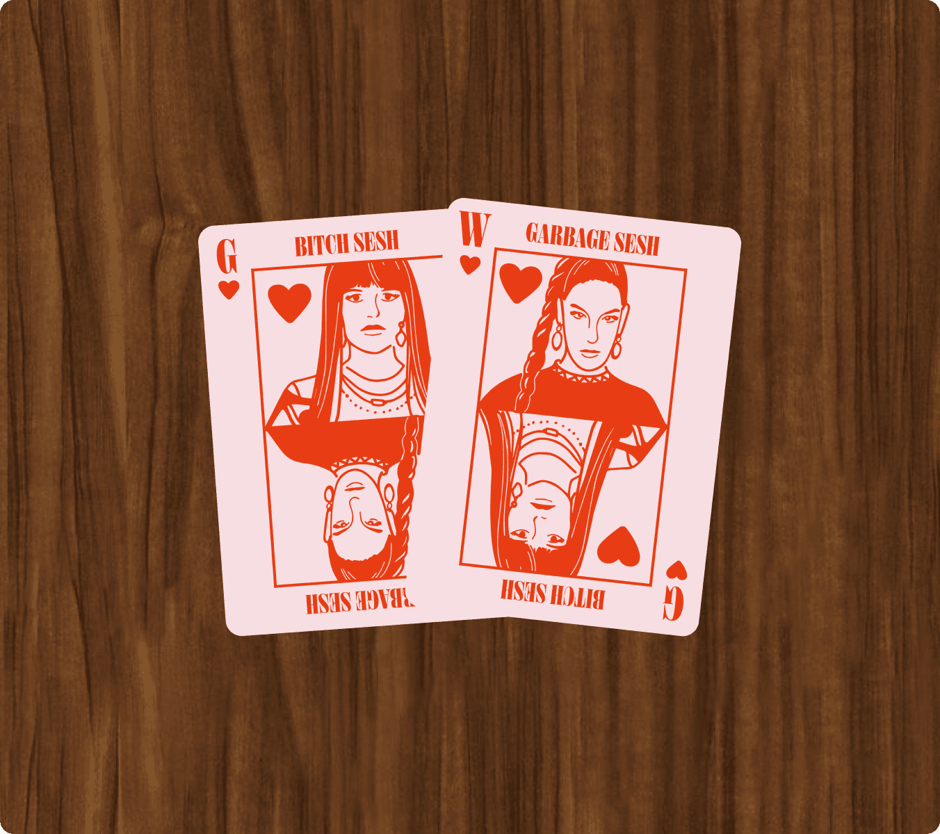 Two custom playing cards, a Queen of Hearts and a Wild card, with illustrated female figures and the phrases "BITCH SESH," "GARBAGE SESH," and "RAGE SESH," on a wooden surface. | Wonderly