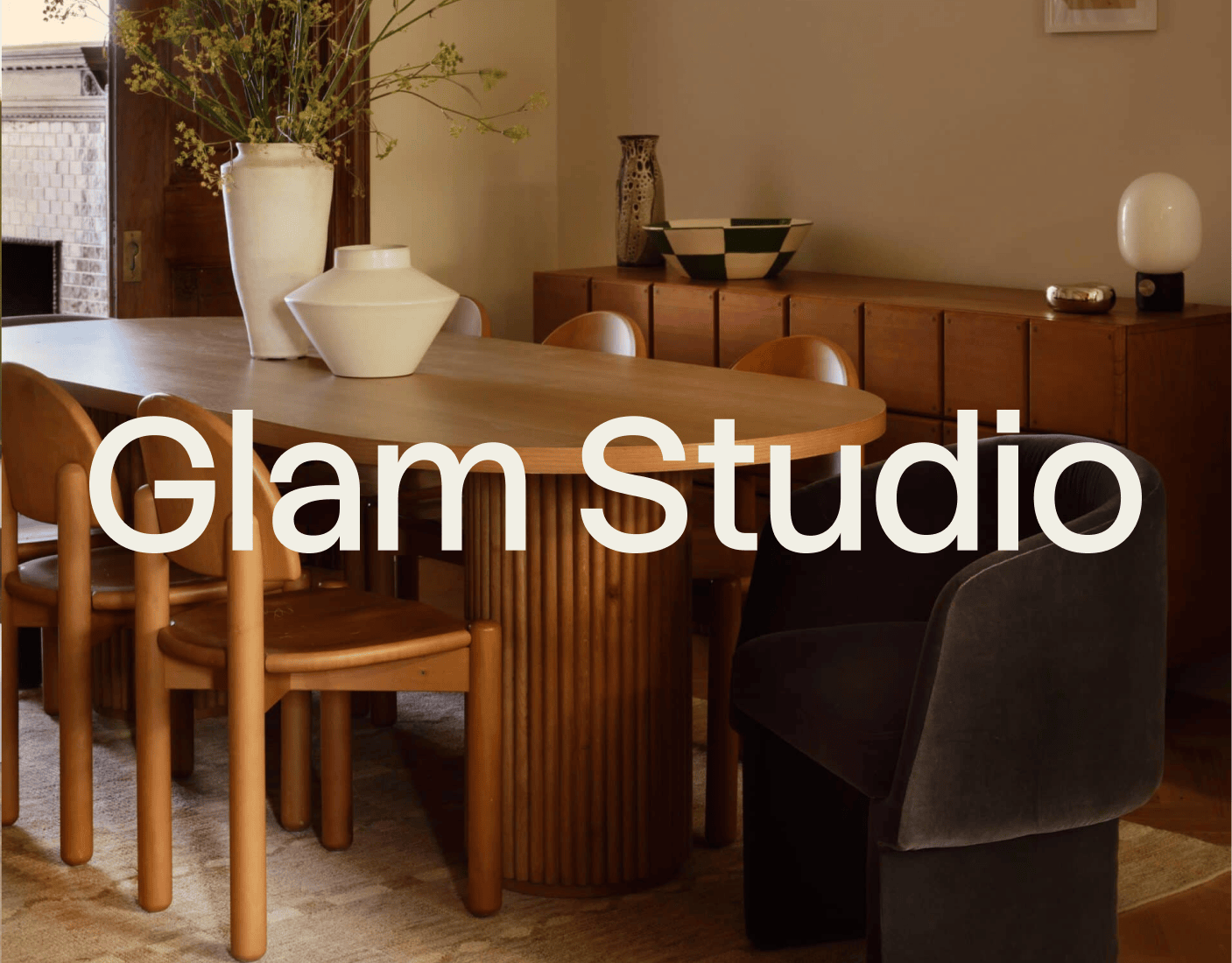A modern dining room features a wooden table with tan chairs, a black chair, decorative vases, and the text "Glam Studio" overlaid. | Wonderly