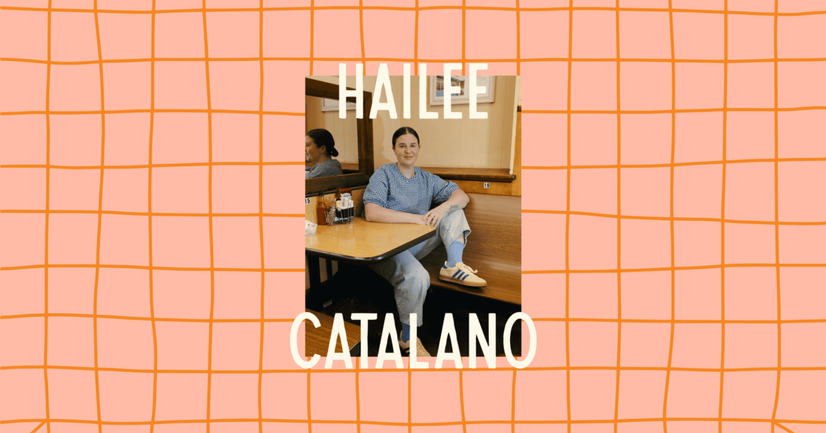 A person sits at a wooden table in a casual setting, wearing a striped shirt and sneakers. The names "Hailee Catalano" are written in large text over the image. | Wonderly