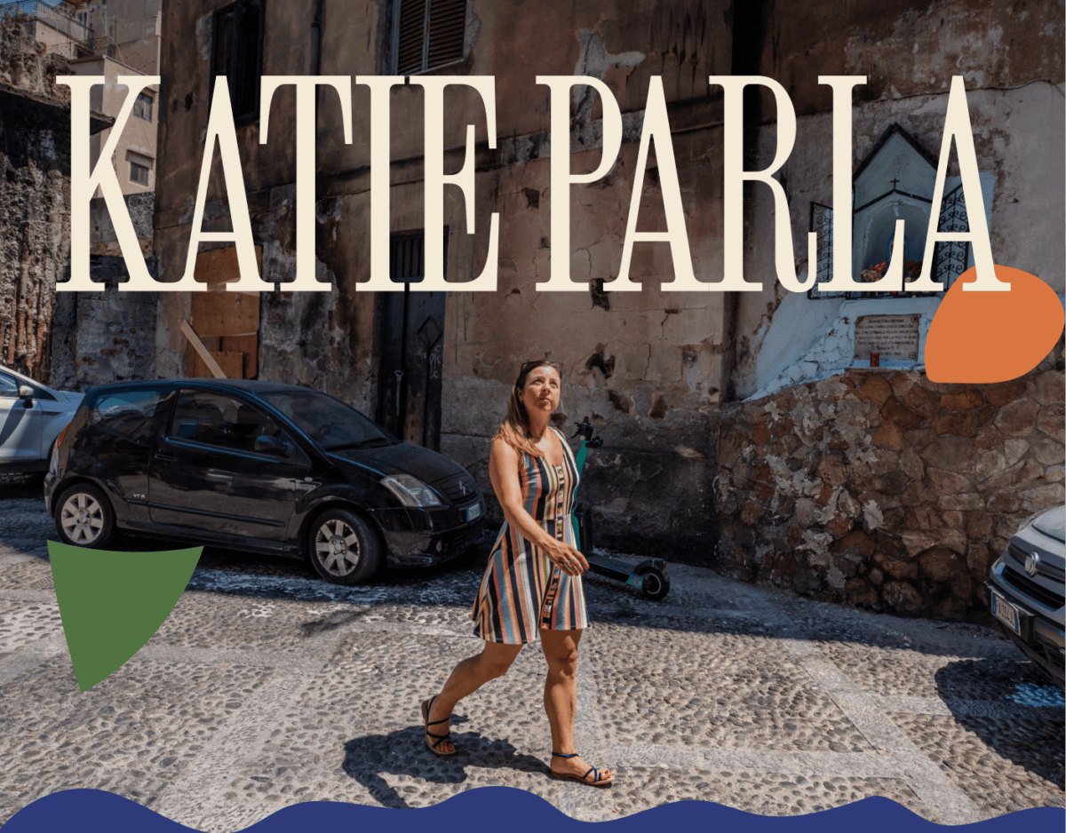 A woman in a striped dress walks on a cobblestone street with parked cars and old buildings; large text reads "KATIE PARLA" above her. | Wonderly