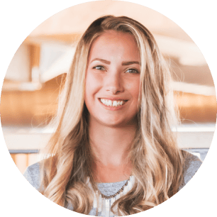 A person with long blonde hair smiling, wearing a gray top, indoors. | Wonderly
