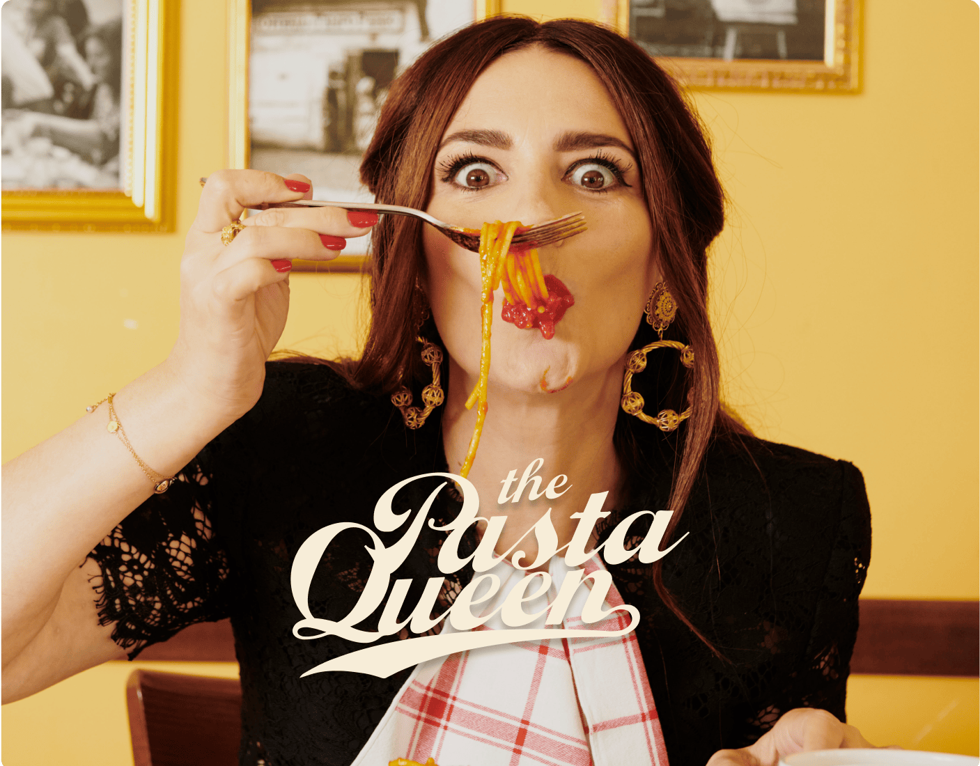 A woman with wide eyes holds a forkful of spaghetti near her mouth, wearing gold earrings and a bib, with “the Pasta Queen” text over the image. | Wonderly