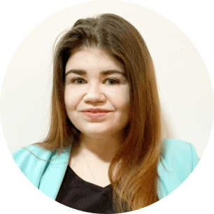 Person with long brown hair wearing a light blue blazer and black top, smiling in front of a plain white background. | Wonderly