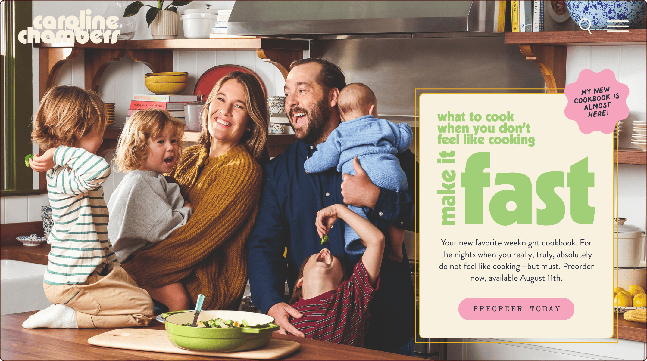 A smiling family of five stands together in a kitchen holding two young children, with a sign promoting a cookbook titled "what to cook when you don't feel like cooking make it fast. | Wonderly